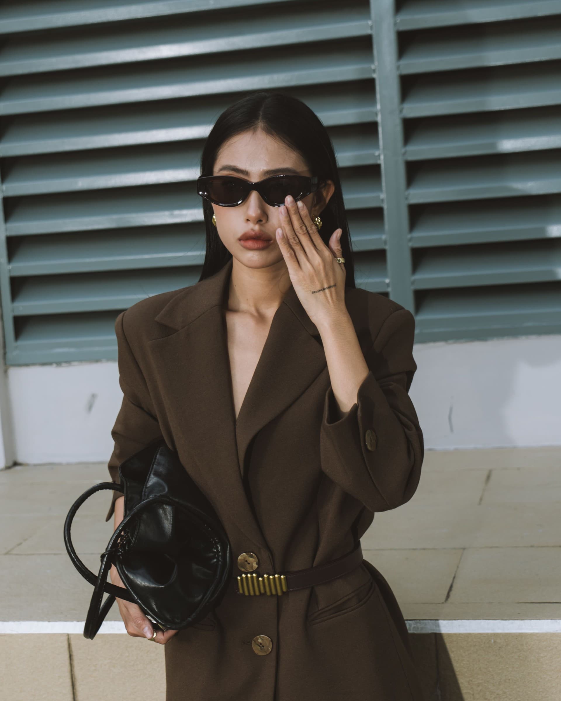 Elevated brown blazer with statement sunglasses and a sculptural black handbag.